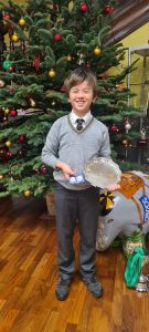 Young boy holding gifts in front of decorated Christmas tree at Inchmarlo.