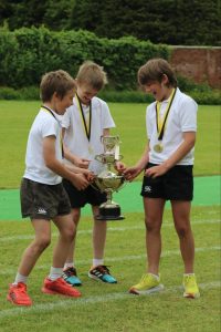 Young athletes receive a trophy on lush green field.