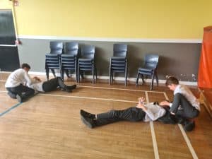 Two students assisting a classmate lying on the floor during an activity at Inchmarlo School.