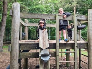 Children playing on outdoor wooden playground at Inchmarlo outdoor activity center.