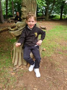 Young boy enjoying outdoor fun at Inchmarlo Gardens, surrounded by trees and sculptures.