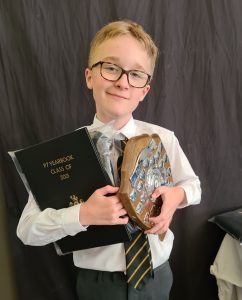 Young student holding a trophy and certificate at Inchmarlo, celebrating academic achievement and school excellence.