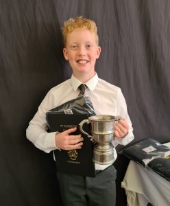 Young boy smiling with trophy at Inchmarlo School event.