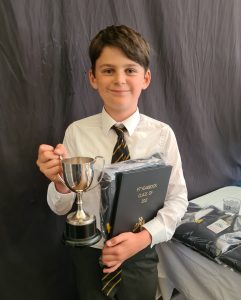 Young boy holding a trophy and book, celebrating achievement at Inchmarlo.