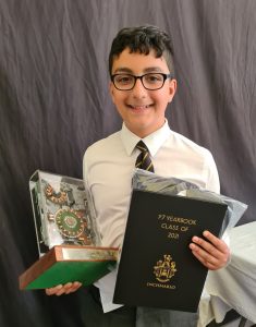 Young boy in school uniform holding awards and a diploma at Inchmarlo.