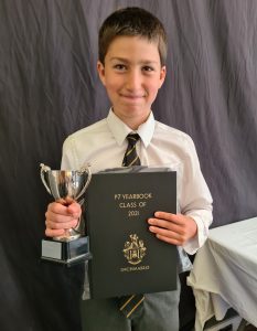 Young boy holding a trophy and certificate for academic achievement.