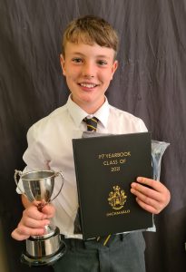 Happy boy holding trophy and diploma after school success.