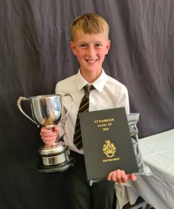 Young student holding trophy and certificate at Inchmarlo Academy.