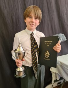 Young student holding trophy and certificate at Inchmarlo school event.