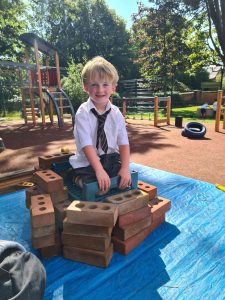 Young boy enjoying outdoor play at Inchmarlo, with colorful playground equipment and lush greenery.