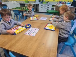 Four children engaging in arts and crafts in a classroom setting with colorful supplies.