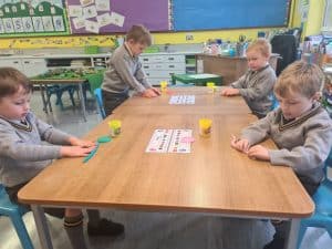 Young children engaged in a creative arts and crafts activity in a colorful classroom.