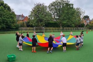 Children enjoying colorful parachute activity outdoors at Inchmarlo School.