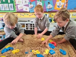 Children playing in a sandpit at Inchmarlo school, promoting early childhood development and outdoor play.
