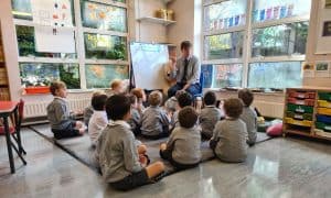 Children learning in a classroom with teacher and educational materials.