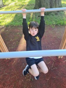 Child hanging from playground bars at Inchmarlo outdoor play area.