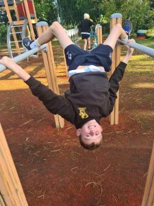 Child hanging upside down on playground equipment at Inchmarlo playground.
