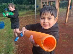 Happy boy playing outdoors with a tube, kids having fun at Inchmarlo outdoor activities.