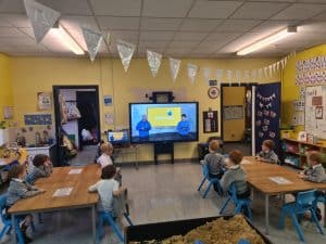 Bright classroom with students learning using a digital screen.