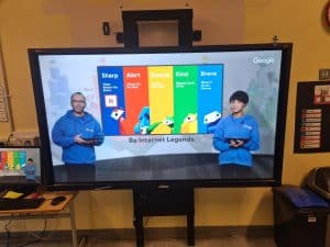 Two staff members presenting at Inchmarlo in front of a digital display board.