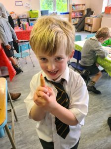Happy schoolboy in classroom holding a small object.