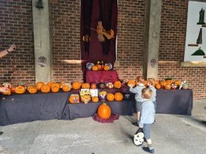 Child playing with pumpkin display at Inchmarlo during autumn festival.