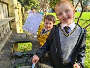 Happy children playing outdoors at Inchmarlo School in a lush green environment.