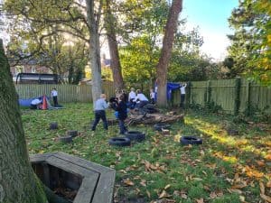 Children playing outdoors in green garden with trees and tire swing.