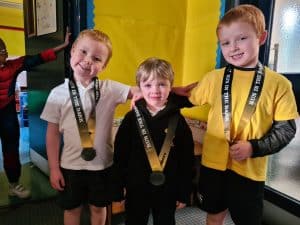 Smiling children with medals at Inchmarlo educational event.