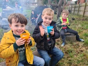 Three children enjoying outdoor drinks at Inchmarlo nature area.