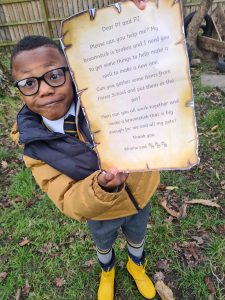 Young boy holding a letter outdoors, focused on education and nature at Inchmarlo.