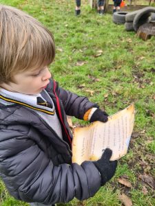 Young child reading outdoors in a park setting.
