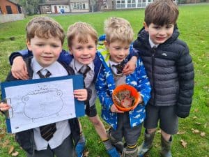 Smiling children holding drawings and a bucket outdoors at Inchmarlo school.