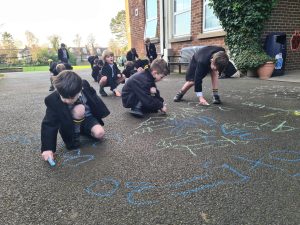 Children drawing with chalk outside at Inchmarlo School, encouraging creativity and outdoor education.