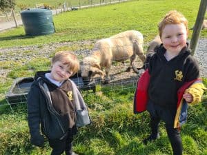 Two children smiling near sheep at Inchmarlo estate in Scotland.