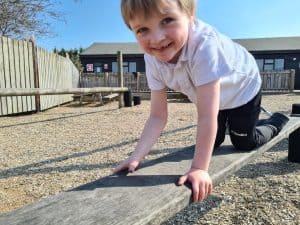 Child playing on outdoor wooden balance beam at Inchmarlo estate, outdoor fun and active play opportunities.
