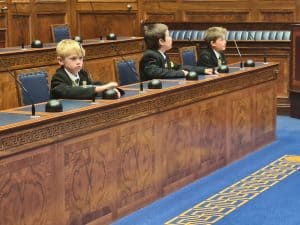 Young children sitting in a formal courtroom setting, likely participating in a mock trial or educational activity.