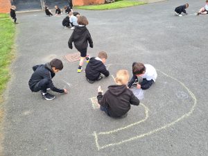 Children drawing on outdoor playground with chalk at Inchmarlo school.