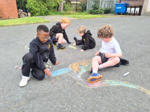 Children drawing with chalk outdoors at Inchmarlo school playground.