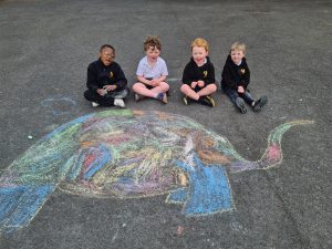 Children drawing on pavement at Inchmarlo with colorful chalk art of an elephant.