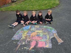 Children sitting on the pavement with colorful chalk drawing at Inchmarlo.