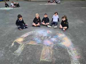 Children drawing colorful chalk artwork outdoors at Inchmarlo school playground.