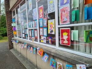 Colorful children's artwork displayed on a classroom window.