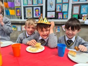 Cheerful kids celebrating birthday at Inchmarlo with cake and party hats.