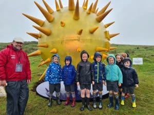 Group of children and adult in front of giant spiky yellow art installation at Inchmarlo.