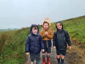 Three children enjoying outdoor adventure at Inchmarlo in the rain. Perfect for family activities in nature.