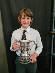 Young boy in school uniform holding a trophy at Inchmarlo School.