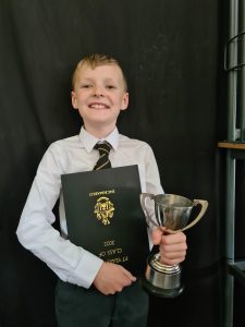 Young boy holding trophy and award certificate at Inchmarlo event.