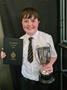 Happy boy holding a trophy and certificate after a school award.