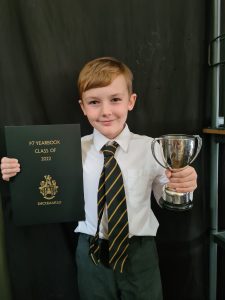 Young student holding a trophy and diploma at Inchmarlo school.